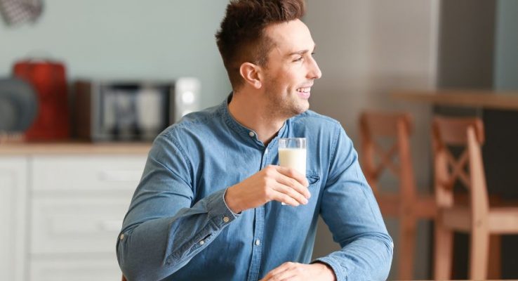 Young man drinking whole milk in the kitchen